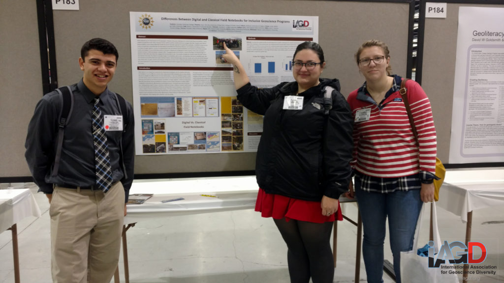 Three students stand in front of their poster, one points to herself in a photo on the poster.