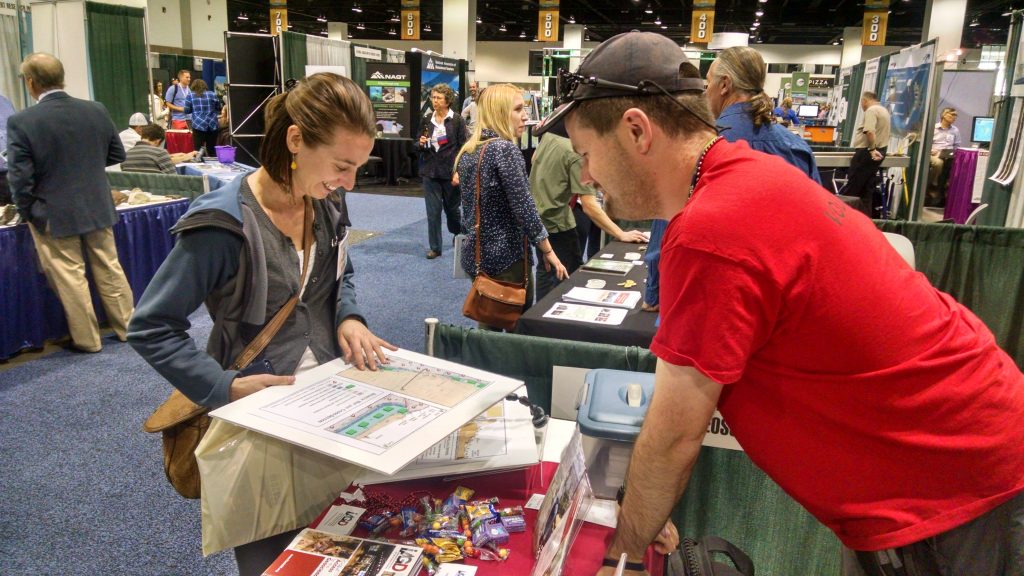 Cole shows a map to a conference attendee at the IAGD booth in the expo hall.