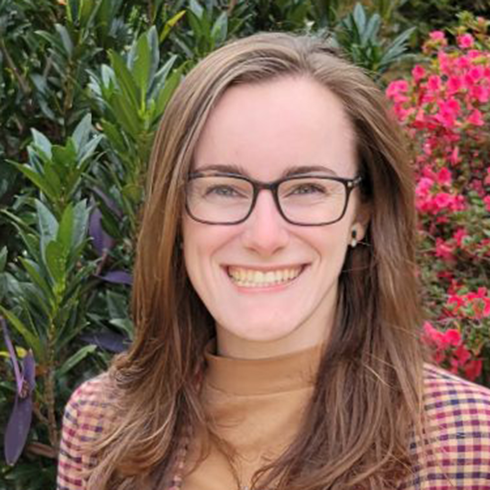 Annie Klyce, a white woman with long brown hair, glasses and a big smile.